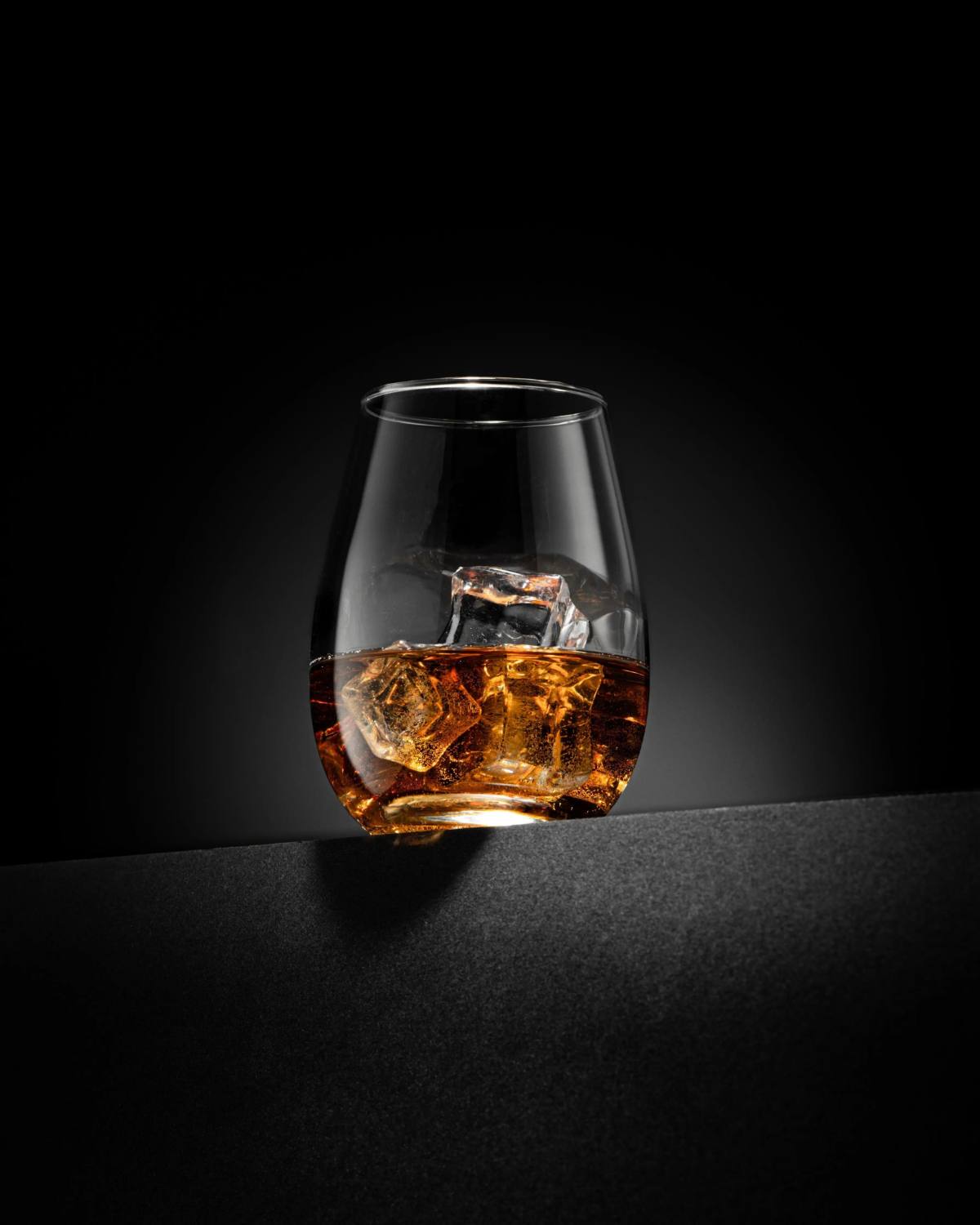 Verre de whisky avec glaçons sur fond sombre, derniers arrivages spiritueux